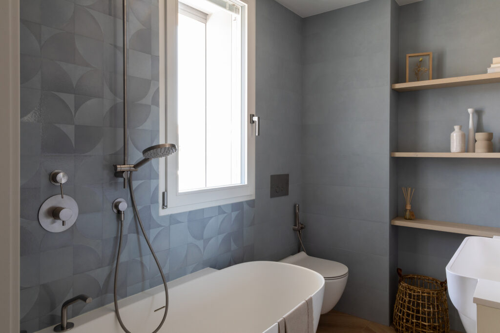stanza da bagno contemporanea con piastrelle azzurre e vasca freestanding