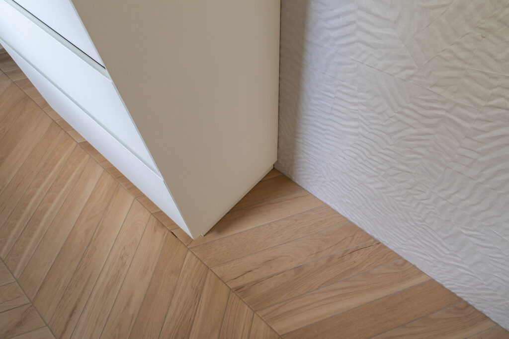 dettaglio parete bagno con piastrelle 3d bianche effetto carta con pavimento effetto legno a spina di pesce
