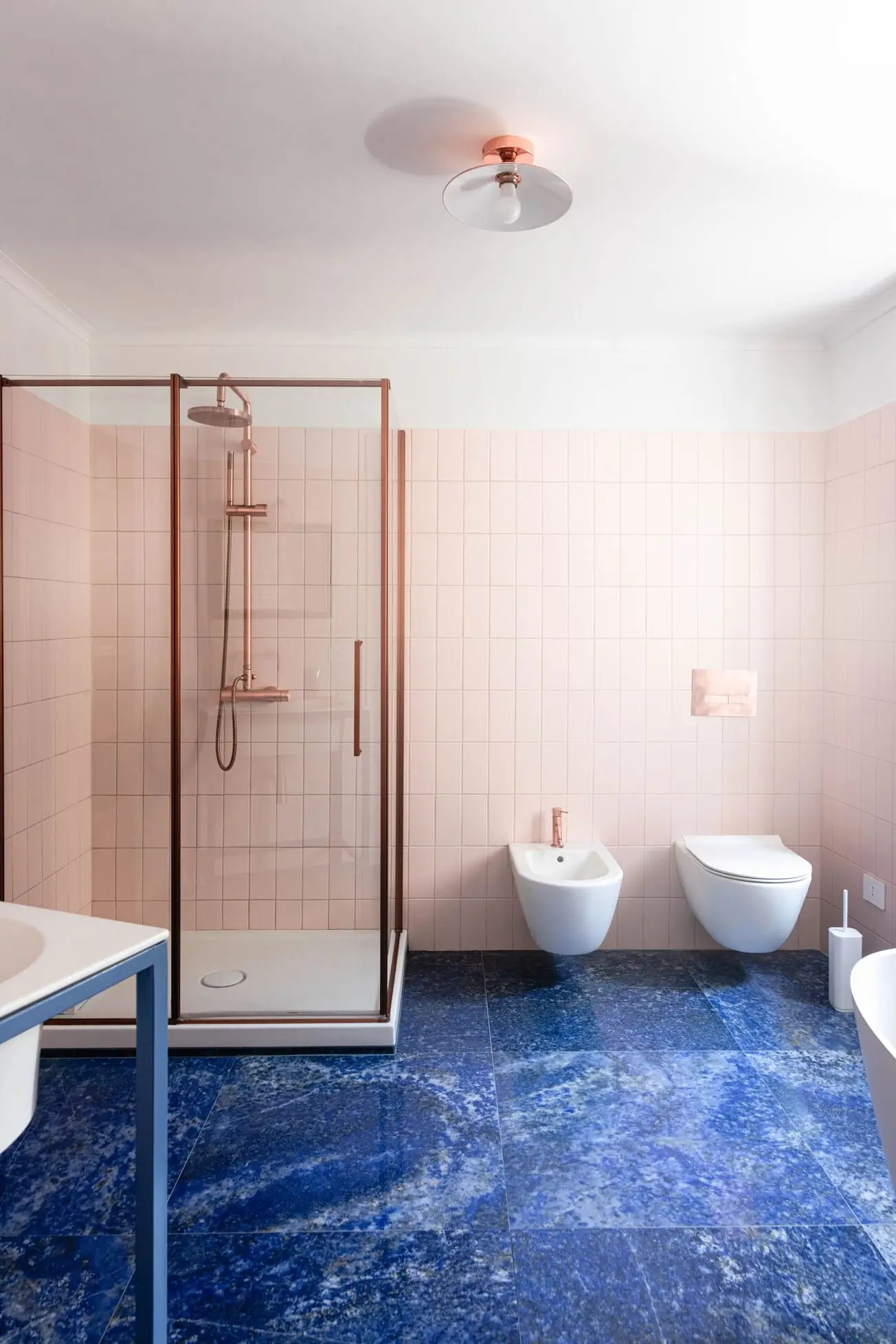 bagno con piastrelle rosa blush e pavimenti blu